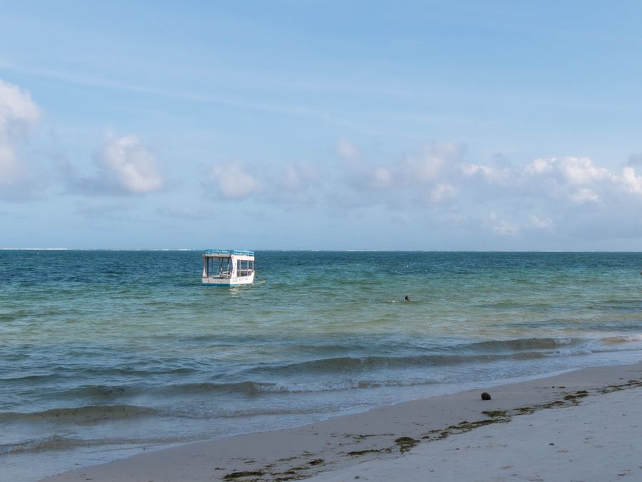 A glass-bottomed boat anchored in turquoise water off the Kenyan coast